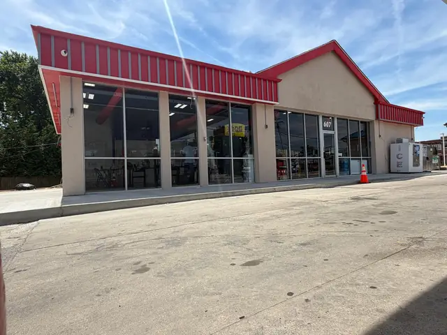 Exterior of the store with new stucco, red metal fascia and concrete apron